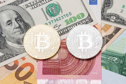Silver and golden bitcoin on euros and dollar background.