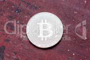 Close up of silver bitcoin on red background.
