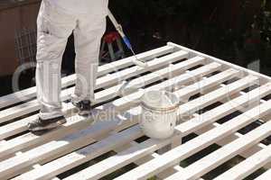 Professional Painter Rolling White Paint Onto The Top of A Home