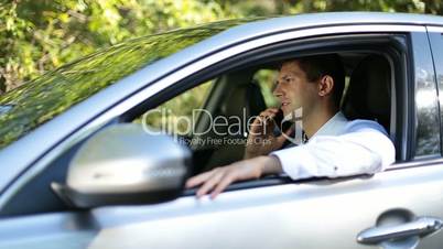 Handsome businessman talking on phone in car