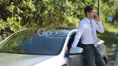 Handsome businessman using mobile phone near car