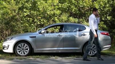 Successful businessman talking on phone near car