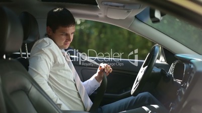 Serious businessman fastening seat belt in car