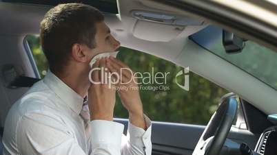 Businessman cleaning lipstick from cheek in car