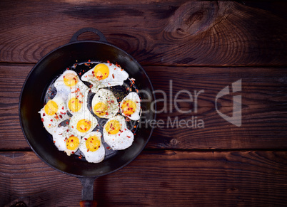 Fried quail eggs in a black cast-iron frying pan