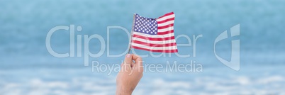 Person holding USA flag against sea background