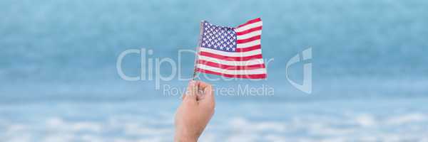 Person holding USA flag against sea background