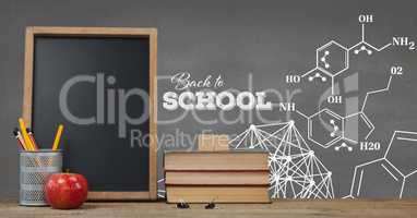 Books on the table against grey blackboard with education and school graphics