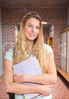 female student holding files in front of lockers in corridor
