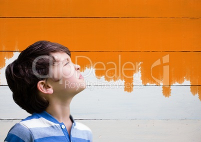 Boy looking upwards next to painted orange wall