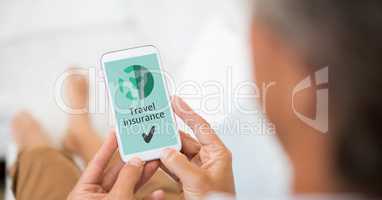 Man holding a phone with travel insurance concept on screen