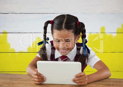 Girl on tablet in front yellow painted background