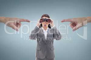 Hands pointing at excited business woman looking through binoculars against blue background
