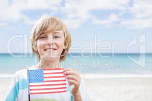 Happy boy holding a USA flag in the beach