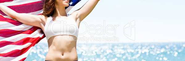 Woman holding USA flag against sea background
