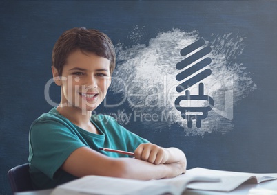 Student boy at table against blue blackboard with school and education graphic