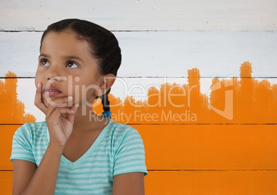 Girl thinking in front of orange painted background