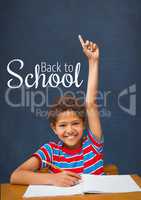 Happy student boy at table raising hand against blue blackboard with back to school text