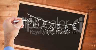 Hand drawing light bulbs on blackboard