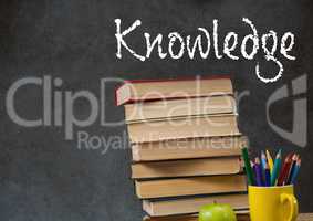 Knowledge text on blackboard with stack of books on desk