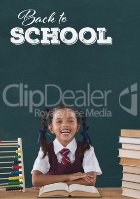 Happy student girl at table against green blackboard with back to school text