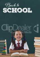 Happy student girl at table against green blackboard with back to school text