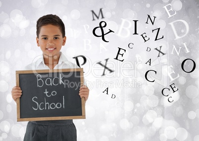 Many letters around Schoolboy holding back to school blackboard in front of bright bokeh background