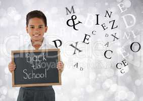 Many letters around Schoolboy holding back to school blackboard in front of bright bokeh background