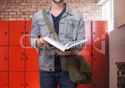 male student holding book in front of lockers