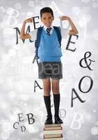 Many letters around Schoolboy flexing strong arms while standing on books and bokeh bright backgroun