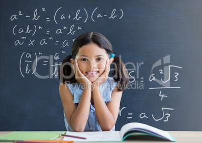 Student girl at table against blue blackboard with education and school graphics