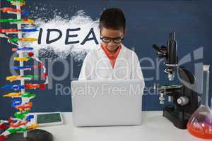 Student boy at table using a computer against blue blackboard with idea text