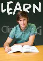 Student boy at table against green blackboard with learn text