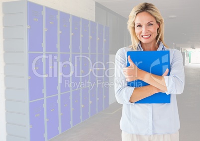 Mature female student holding book in front of lockers