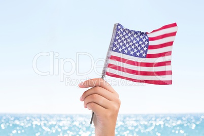 Person holding a USA flag in the beach