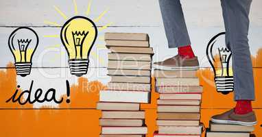 Feet walking up book stairs with colorful light bulb graphics and orange painted wall