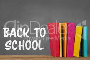Books on the table against grey blackboard with back to school text