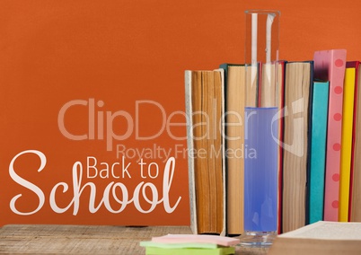 Books on the table against orange blackboard with back to school text