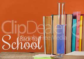 Books on the table against orange blackboard with back to school text