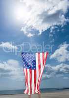 Man holding a USA flag in the beach