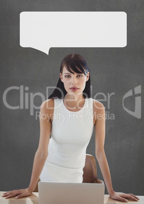 Business woman at table with speech bubble against grey background