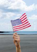 Man holding a USA flag in the beach