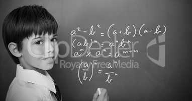 Boy writing math equations on blackboard