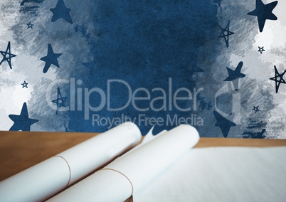 Scrolls of paper plans on desk with blackboard and stars