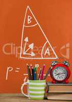 Books on the table against orange blackboard with education and school graphics