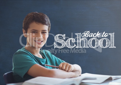 Student boy at table against blue blackboard with back to school text