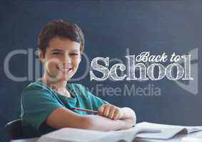 Student boy at table against blue blackboard with back to school text