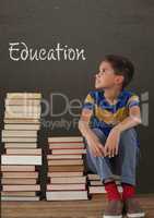 Student boy sitting on table against grey blackboard with education text