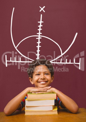 Happy student boy at table against red blackboard with education and school graphic