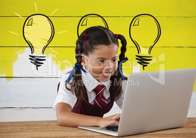 Schoolgirl on laptop with light bulbs on painted yellow wall